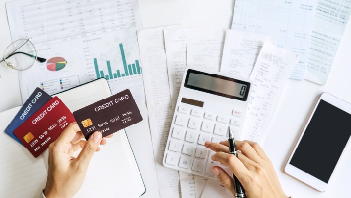 person calculating multiple credit card bill using a calculator