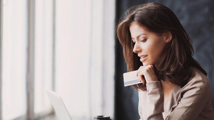 woman holding credit card and using laptop