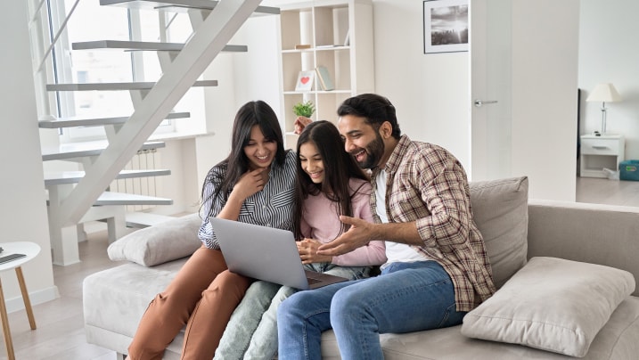 family of 3 having fun using laptop at home.