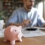 man working on his laptop with piggybank on desk