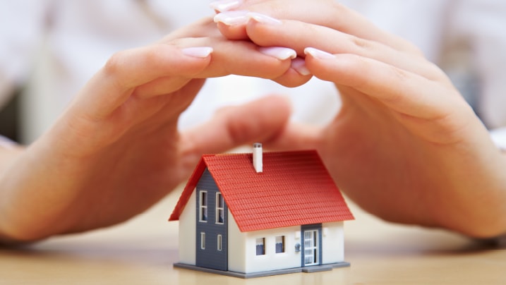 person's hands saving small house with a roof