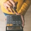 person using a calculator with a pen in hand