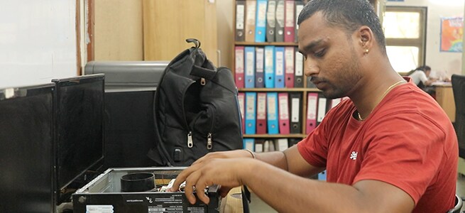 Srikanth fixes a computer for his client. Srikanth has been running computer hardware and service business from Pune.